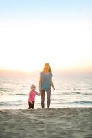 Healthy mother and baby girl walking on beach