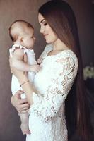 madre con cabello oscuro posando con su pequeño bebé adorable foto