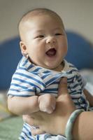 manos de la madre sosteniendo feliz sonriente bebé asiático foto