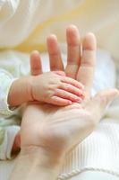 la mano de los padres sostiene la palma del bebé