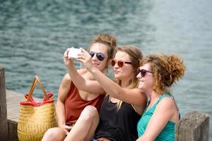 tres mujeres jóvenes en la playa con su teléfono