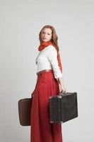 mujer en falda roja vintage con maletas