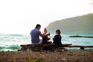 padre sentado con sus hijos en la playa