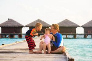 padre con hijos en vacaciones tropicales foto