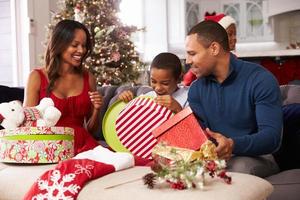 familia abriendo regalos de navidad en casa juntos foto