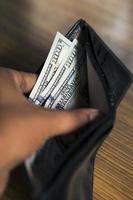 Hands showing money inside a wallet.