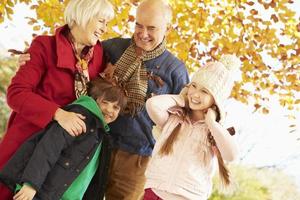 abuelos y nietos jugando bajo el árbol de otoño