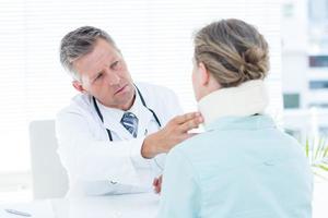 Doctor checking neck brace of his patient photo