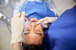 Cerca del dentista que controla los dientes del paciente masculino