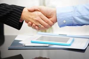 businessman and businesswoman are handshaking over documents and presentation photo
