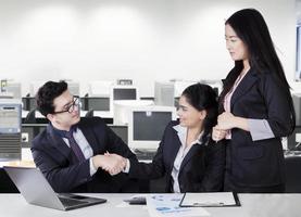 Businesspeople shaking hands in office room