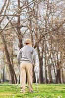 Elderly gentleman with crutches, walking in park