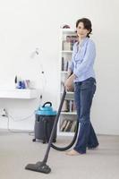 Smiling woman vacuuming living room photo