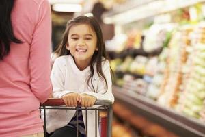 Close-up of mother pushing happy daughter in a store cart photo