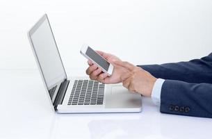 Businessman hands holding mobile phone with laptop computer photo