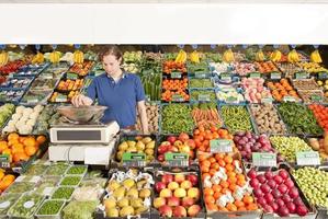 Un hombre que trabajaba en una tienda de comestibles verdes que pesaba verduras foto