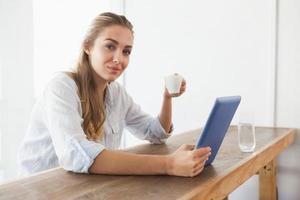 Pretty blonde having coffee while using tablet photo