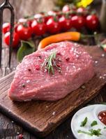 Raw beef steak on wooden table photo