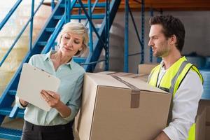 Warehouse manager and worker looking at clipboard photo