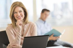 Thoughtful businesswoman smiling in office photo
