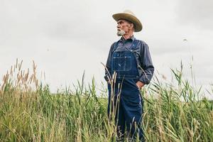 Senior hombre agricultor con sombrero de pie en la granja foto