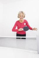 feliz mujer senior jugando tenis de mesa