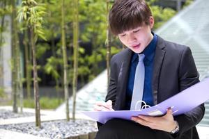 Young Asian male business executive holding file photo