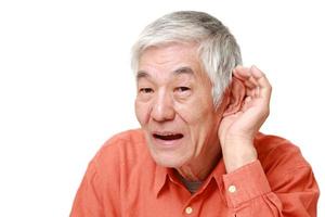senior Japanese man with hand behind ear listening closely