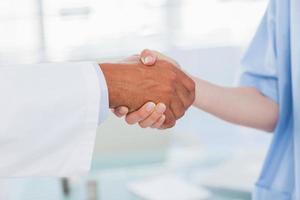 Hands of a doctor and nurse shaking hands photo