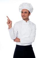 chef masculino mirando y apuntando lejos foto