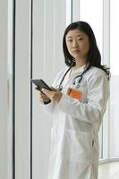 joven doctora asiática sosteniendo una tableta, vertical foto