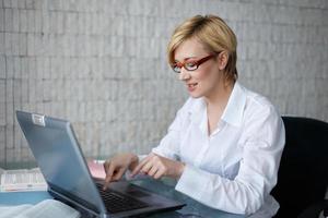 Blonde businesswoman in glasses typing photo