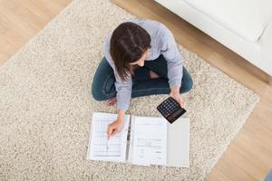 Woman Calculating Home Finances On Rug photo