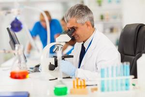 senior medical researcher looking through the microscope photo