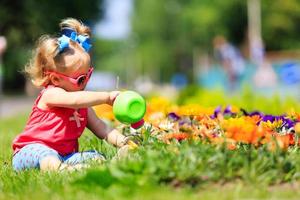 little girl watering flowers in summer