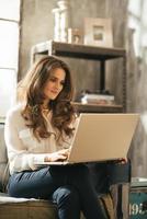 mujer joven usando laptop mientras está sentado en el apartamento tipo loft