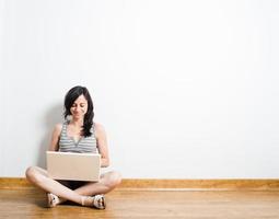 mujer joven con laptop en un piso de madera