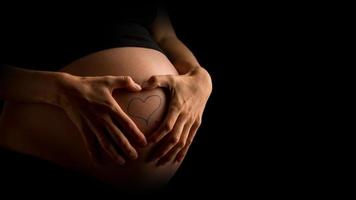mujer embarazada mostrando tatuaje de corazón en el vientre foto