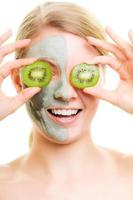 Skin care. Woman in clay mask with kiwi on face photo