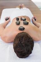 hombre recibiendo masaje con piedras en el centro de spa foto