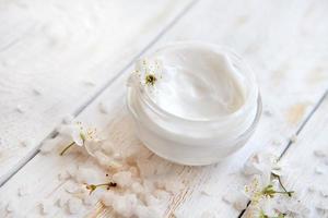 Pot of beauty cream surrounded by flowers and sea salt photo