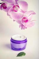 Face/hand cream jar and purple orchid flowers, vertical shot