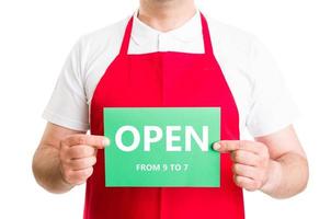 Supermarket male employee holding open 9 to 7 sign photo