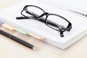 Office table with glasses over notepad photo