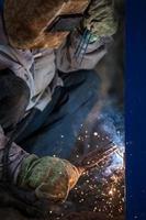 Trabajador de soldador de arco en máscara protectora de soldadura de construcción metálica