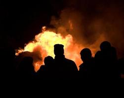 Silhouetted people around a bonfire at night photo