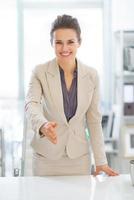 Business woman stretching hand for handshake in office