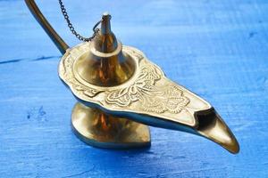 Magical genie lamp isolated on a blue wooden background photo