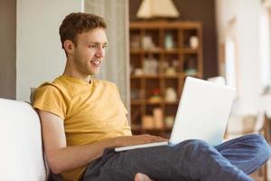 Young man using laptop on his couch photo