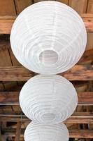 Tres linternas de papel blanco (lampoons) en techo de madera foto